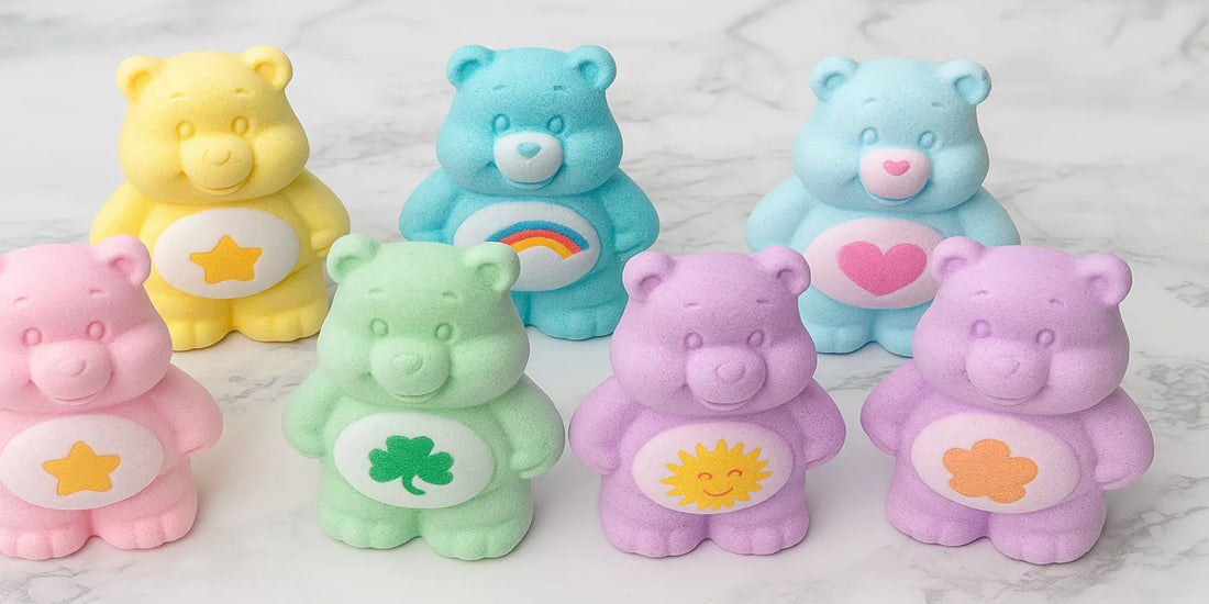 Six pastel-colored bear-shaped bath bombs with unique belly symbols, arranged on a white marble surface, showcasing playful and scented designs.