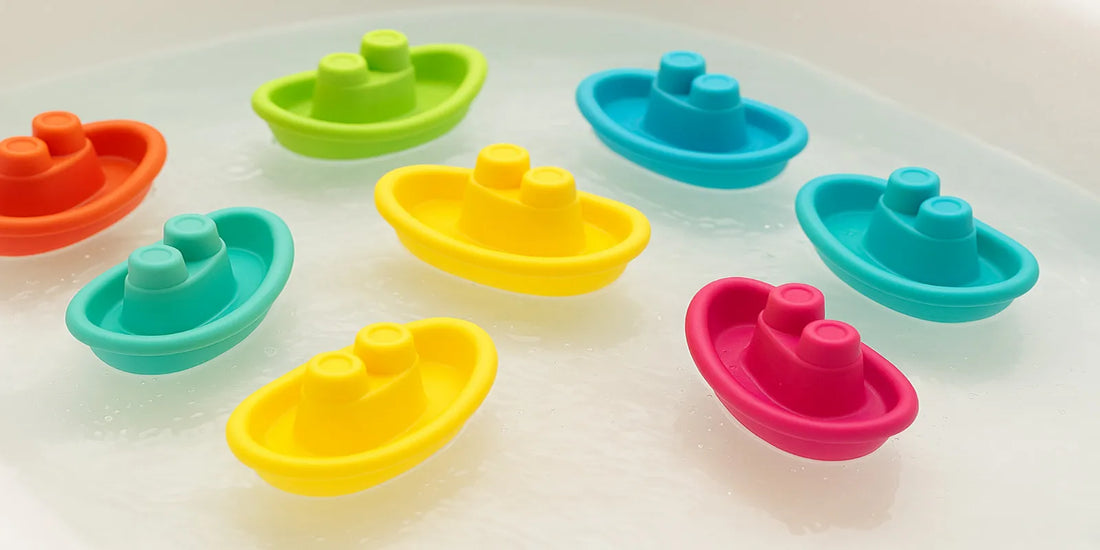 Nine colorful BPA-free plastic toy boats floating in a bathtub, designed for safe and mold-free bath play for infants and toddlers in 2025.